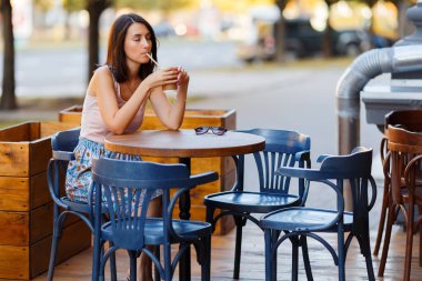 Bir yaz teras bir Cafe de oturup bir sıcak kahve ile güzel bir gülümseyen mutlu Bayan portresi. Genç bir kız oturuyor ve bir restoran masada kahve içme.