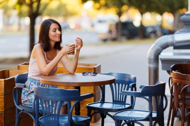 Bir yaz teras bir Cafe de oturup bir sıcak kahve ile güzel bir gülümseyen mutlu Bayan portresi. Genç bir kız oturuyor ve bir restoran masada kahve içme.
