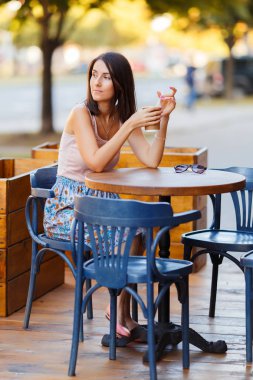 Bir yaz teras bir Cafe de oturup bir sıcak kahve ile güzel bir gülümseyen mutlu Bayan portresi. Genç bir kız oturuyor ve bir restoran masada kahve içme.