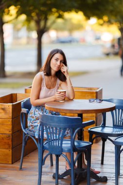 Bir yaz teras bir Cafe de oturup bir sıcak kahve ile güzel bir gülümseyen mutlu Bayan portresi. Genç bir kız oturuyor ve bir restoran masada kahve içme.