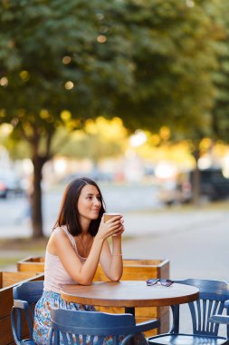 Bir yaz teras bir Cafe de oturup bir sıcak kahve ile güzel bir gülümseyen mutlu Bayan portresi. Genç bir kız oturuyor ve bir restoran masada kahve içme.