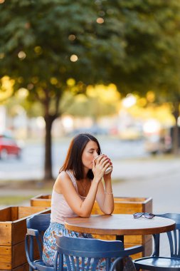Bir yaz teras bir Cafe de oturup bir sıcak kahve ile güzel bir gülümseyen mutlu Bayan portresi. Genç bir kız oturuyor ve bir restoran masada kahve içme.