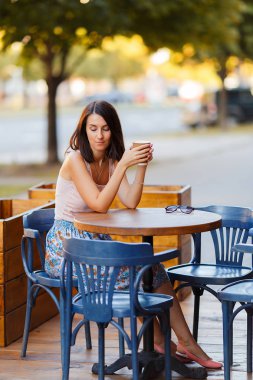Bir yaz teras bir Cafe de oturup bir sıcak kahve ile güzel bir gülümseyen mutlu Bayan portresi. Genç bir kız oturuyor ve bir restoran masada kahve içme.