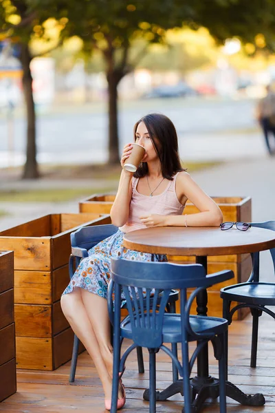 Bir yaz teras bir Cafe de oturup bir sıcak kahve ile güzel bir gülümseyen mutlu Bayan portresi. Genç bir kız oturuyor ve bir restoran masada kahve içme.