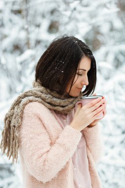 Kış ormandaki yağan kar altında kahve içme pembe kazak kız