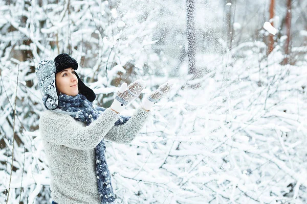 Hermosa chica juega con la nieve que cae en el bosque de invierno — Foto de Stock