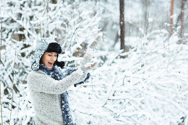 Hermosa chica juega con la nieve que cae en el bosque de invierno — Foto de Stock