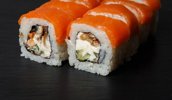 Philadelphia roll sushi with salmon, avocado, cream cheese served on black stone slate — Stock Photo, Image