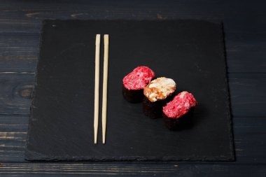 Gunkan Maki Sushi üzerinde bambu Suşi çubukları ile siyah kayrak