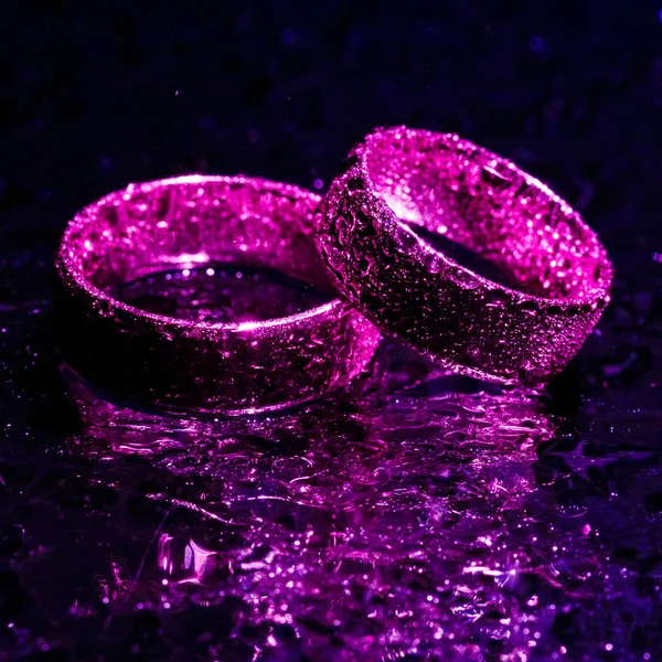 Beautiful wedding rings with violet neon lights — Stock Photo, Image