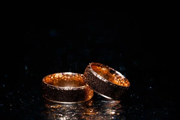 Mooie bruiloft gouden ringen op donkere achtergrond — Stockfoto