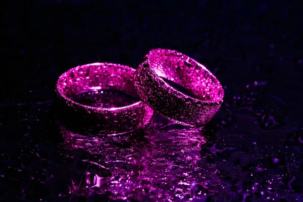 Schöne Eheringe mit violettem Neonlicht — Stockfoto