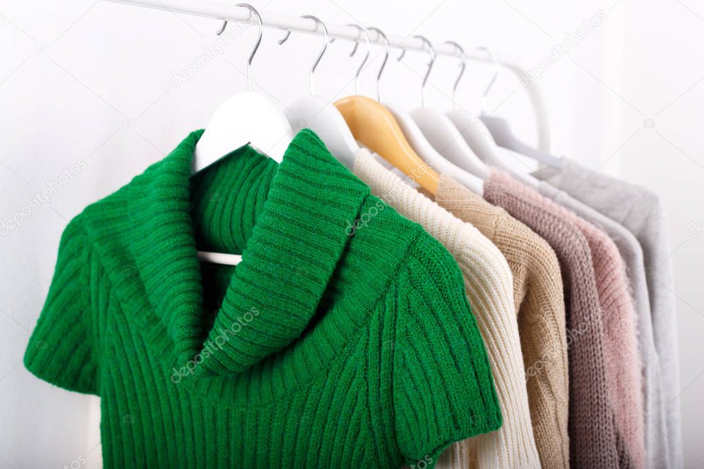 Warm knitted, autumn, winter clothes hanging on a rack, trending concept