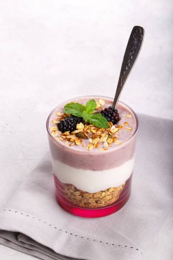Granola ve bir bardak, sağlıklı tatlı Yunan yoğurt ile BlackBerry güler yüzlü