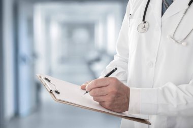 Bir erkek Doktor hastanede tıbbi formu ayakta dolduruyor Pano tutarak yakın çekim