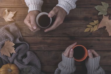 İki fincan çay ya da kahve masada tutarak aşk içinde sonbahar yaprakları ile kaplı