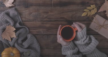 Holding sıcak kahve veya çay battaniye erkek elleri ve üzerinde eski ahşap arka plan vintage Tönning sonbahar sonbahar yaprakları kavramı relax