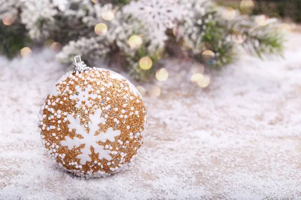 Close up of Christmas golden decoration on snow fir tree copy space