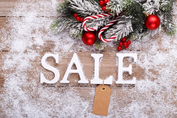 Word Sale wooden letters on snow wooden background with fir tree branch and decorations winter holidays