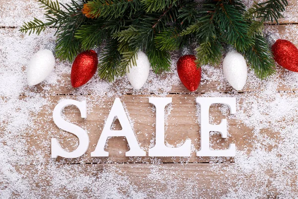 Word Sale wooden letters on snow wooden background with fir tree branch and decorations winter holidays