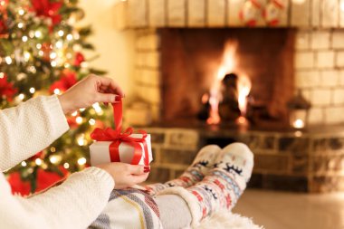Şömine ve Noel ağacı bir hediye kutusu tatil rahat kavramı holding tarafından oturan kadın