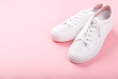 Açık pembe arka planda beyaz yumuşak deri spor ayakkabılar Kadın modası