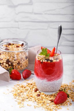 Çilek soslu Chia pudingi. Beyaz rusik arka planda ev yapımı granola.
