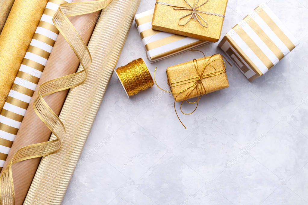 Golden glossy wrapping paper rolls and gift boxes