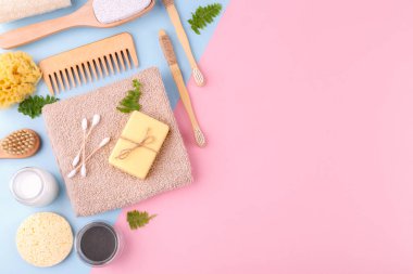 Sıfır atık tekrar kullanılabilir banyo öğeleri mavi pembe arka plan, ahşap tarak, diş fırçası, deniz süngeri, kulak çubuğu, katı sabun, shea veya hindistan cevizi yağı, düz kopya alanı