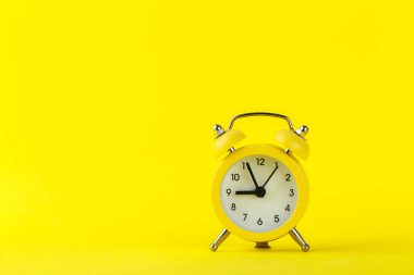 Sarı arkaplanda küçük bir çalar saat, dokuza beş kala çalıyor, kopyala boşluk