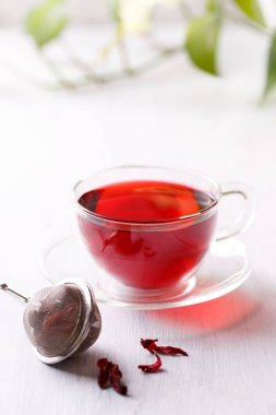 Bahçedeki beyaz ahşap masanın üzerinde şeffaf bardakta sağIıklı amber çayı.