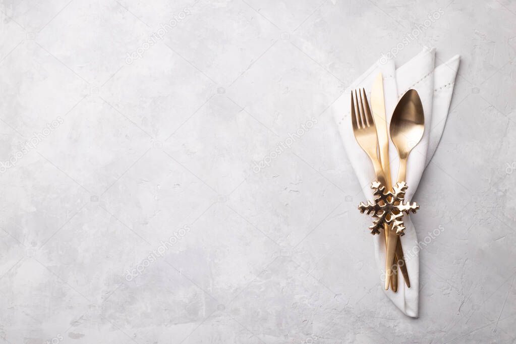 Christmas or new year table setting with golden cutlery on white stone table, card or menu template copy space flat lay