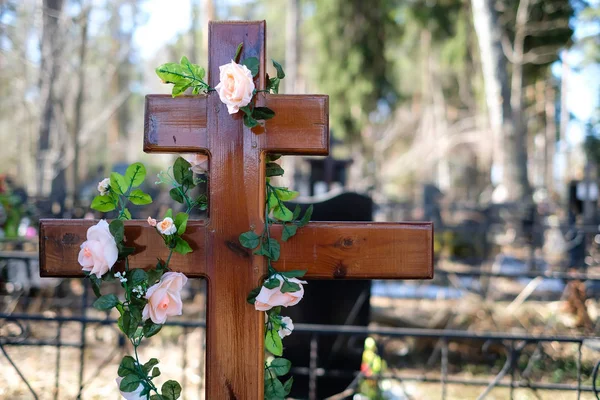 Yapay çiçek çelenk veya gül bahar mezarına çarmıhta çelenk. Mezarlık süslemeleri.