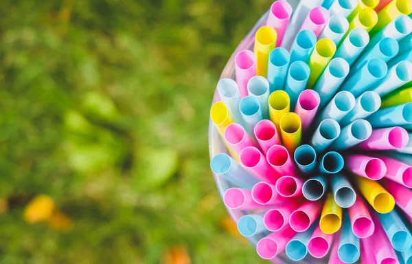 Üstten görünüm parlak renkli kokteyl içecek payet ve büyük bardakta yeşil çim yaz arka plan üzerinde bir araya tüpler. Partiye Hazırlık