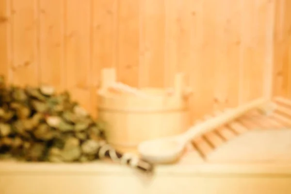 Blurred background of wooden bucket, a birch broom and other accessories in a finnish classic sauna or russian bath. Free space on a wooden wall