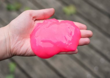 Elinde pembe anti stres oyuncak balçık. Endişe ve stresle mücadele. Çocuklar için yaratıcı oyun deneyi.