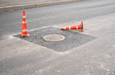 Bir asfalt yolda kırmızı ve beyaz trafik konisi. Yol çalışmaları, asfalt tamiri. Yolda kaza uyarısı.