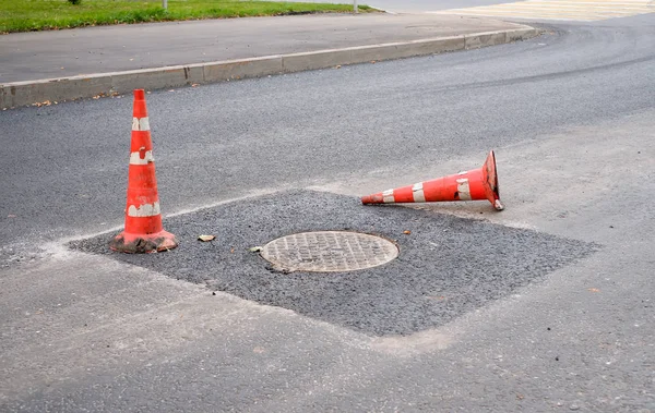 Bir asfalt yolda kırmızı ve beyaz trafik konisi. Yol çalışmaları, asfalt tamiri. Yolda kaza uyarısı.