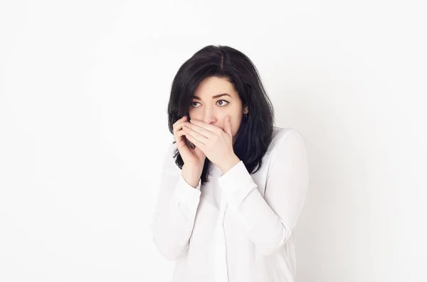 Una joven con una blusa blanca está hablando por teléfono, cubriéndose la boca con la mano. Ella cuenta un secreto o relata rumores y chismes . —  Fotos de Stock