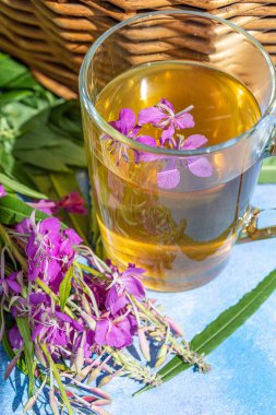 Geleneksel Rus bitkisi şeffaf bir fincanda Ivan çayı içer. Yakın plan, Ivan çayı, ateş otu, hasır sepet arka plan.