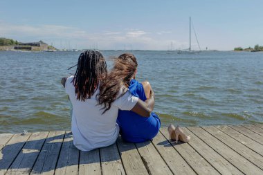 Deniz kıyısındaki bir rıhtımda. Birkaç tane de açık havada. Karışık sevgililer, Afrikalı erkek ve Avrupalı Kafkas kadın.