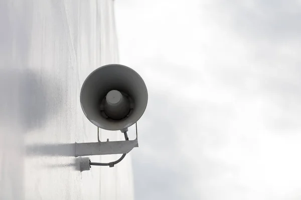 White megaphone, loud speaker close-up. Hanging on the wall.