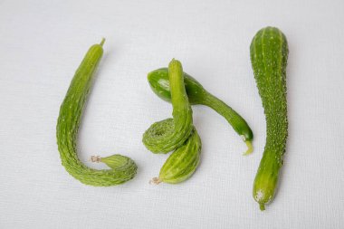 Beyaz arka planda uzun, eğri büğrü, taze salatalıklar..