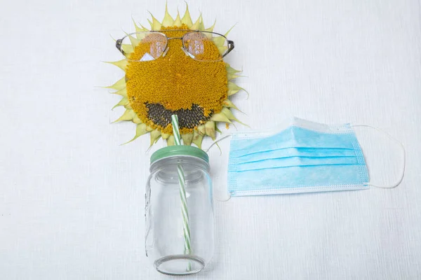 Girasol con gafas de lectura, máscara médica y tarro de batido... concepto, merienda, comida, comida en público durante el coronavirus, sobre un fondo blanco, hay un lugar para el texto — Foto de Stock