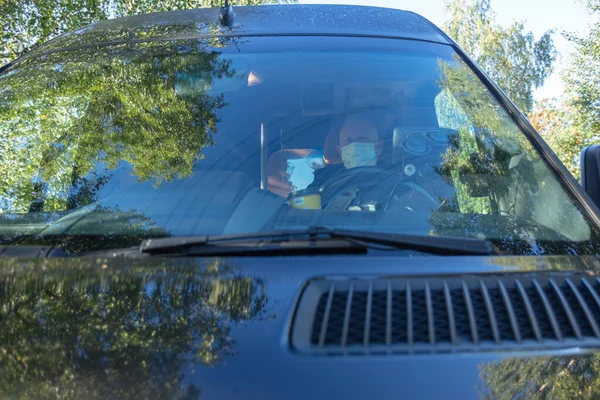 Driver in a medical mask leads a black bus Safe driving during a pandemic, protection against coronavirus