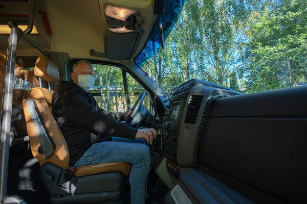 Driver in a medical mask leads a black bus Safe driving during a pandemic, protection against coronavirus