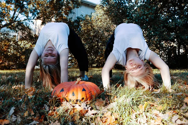 Wo ragazze, capelli biondi, fidanzate, accanto a una grande zucca per Halloween. — Foto Stock