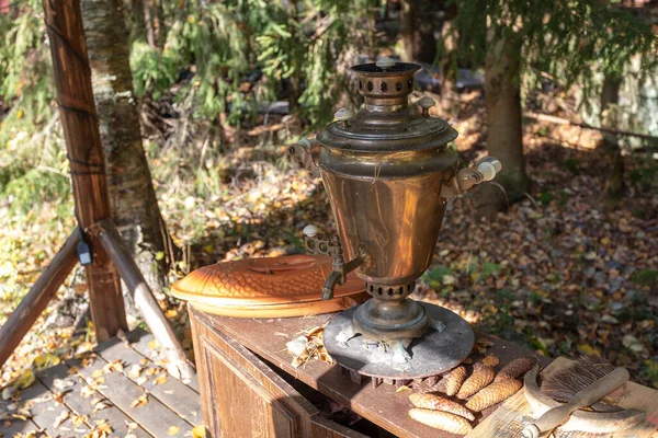 Samovar vintage, de pie sobre la mesita de noche y esperando a ser derretido con conos de abeto, al aire libre. en el fondo del bosque —  Fotos de Stock