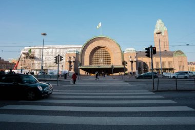Helsinki, Uusimaa, Finlandiya 2 Ekim 2020 'de tren istasyonunda, ana girişin heykellerini süsleyen tıbbi maskeler takan insanlar. Sonbahar, güneşli bir gün. Coronavirus Enfeksiyon Tehlike Konsepti