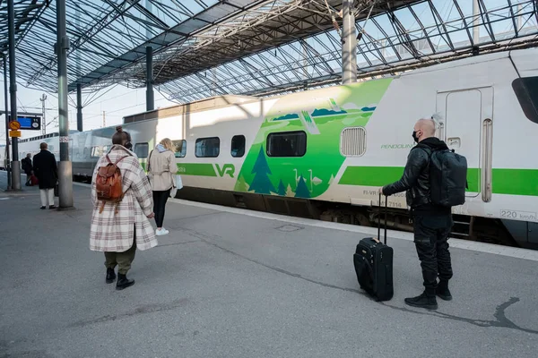 Helsinki, Uusimaa, Finlandiya 2 Ekim 2020 'de tren istasyonunda sağlık maskesi takan insanlar. Sonbahar, güneşli bir gün. Coronavirus Enfeksiyon Tehlike Konsepti